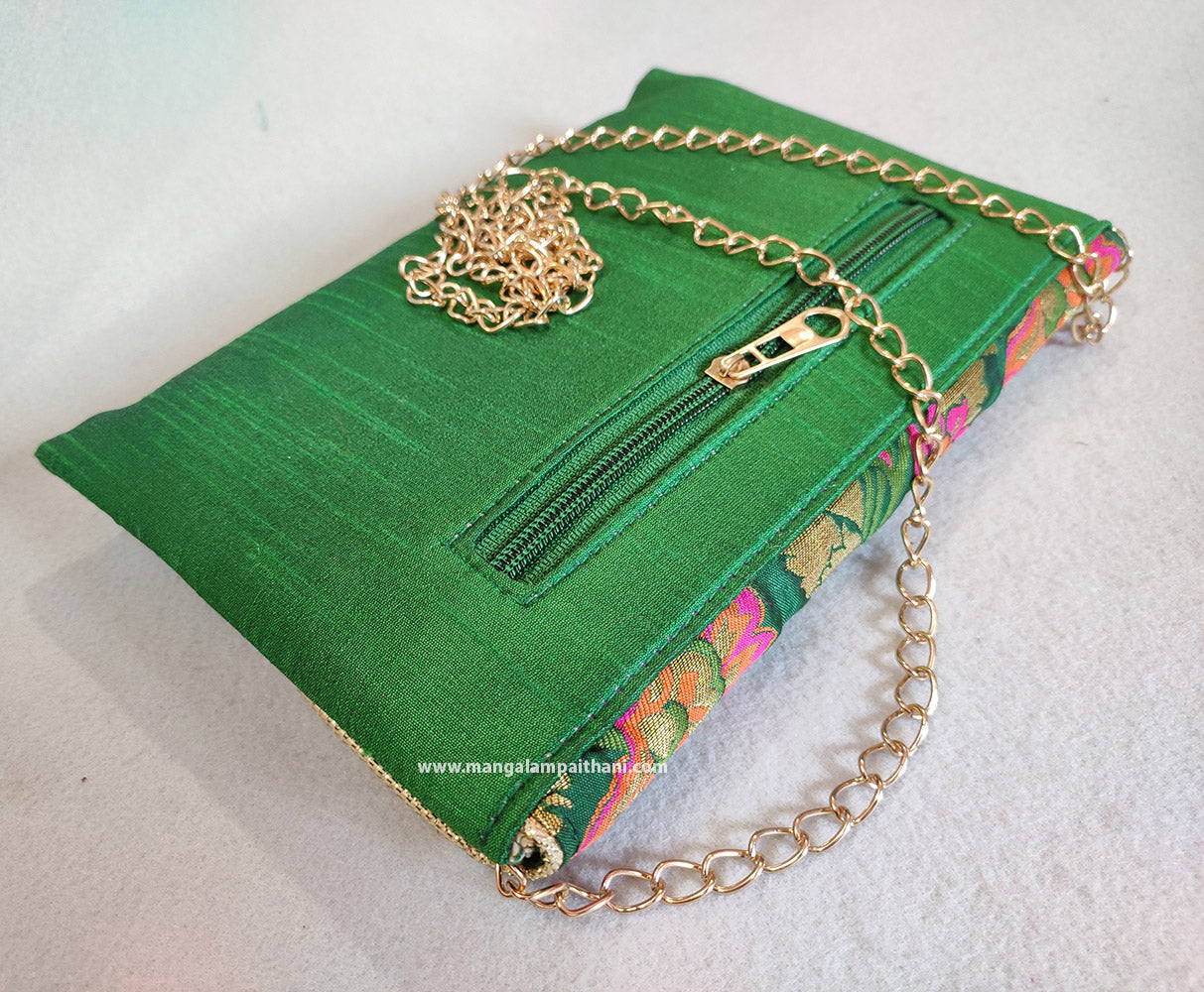 clutch purse with a floral design and a gold chain strap.