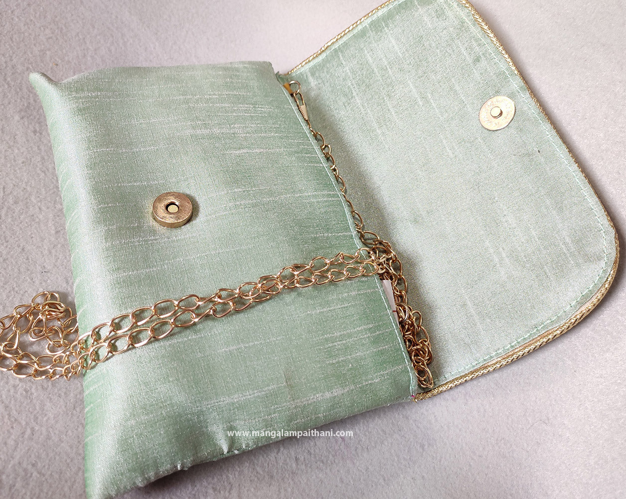 clutch purse with a floral design and a gold chain strap.