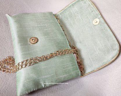 clutch purse with a floral design and a gold chain strap.