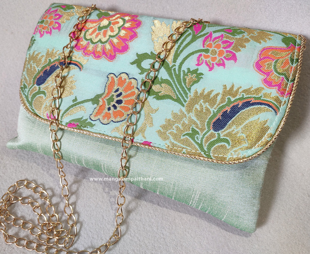 A blue clutch purse with a floral design and a detachable gold chain strap.