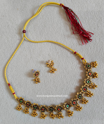 A gold-plated choker necklace with multicolored floral patterns and a pair of matching earrings.