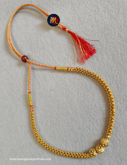 Gold plated choker necklace with a red and yellow design and a tassel at the end